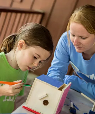 Mom and daughter painting a birdhouse