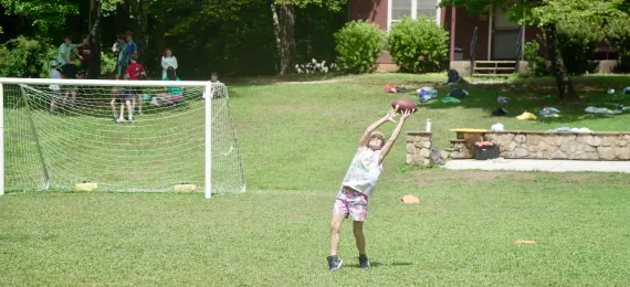 Camper catching a football on Hilton's field
